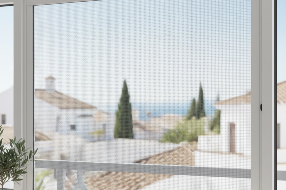 Mosquitera enrollable con malla de fibra de vidrio instalada en una ventana de una vivienda de Viladecans